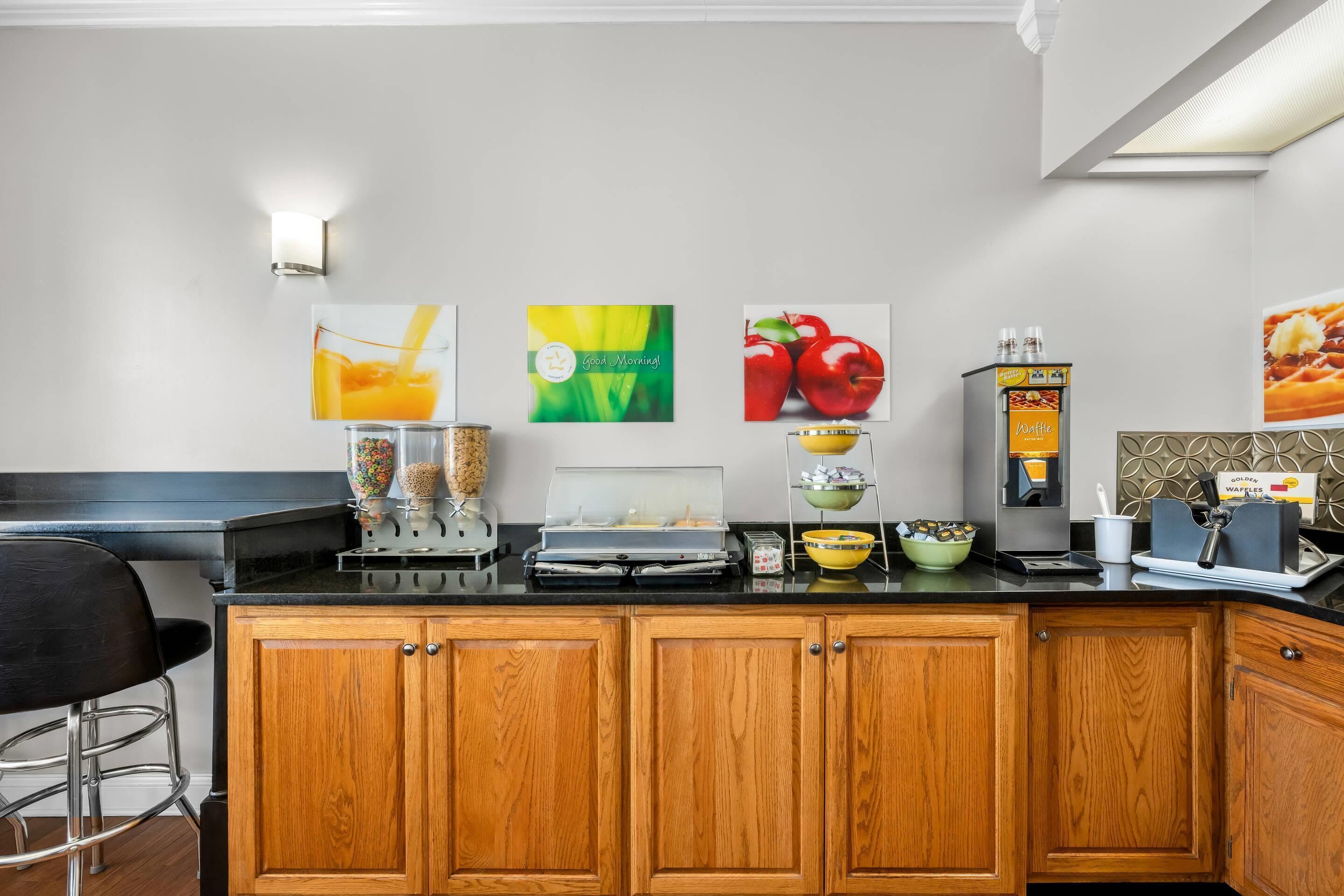 A kitchen with wooden cabinets, a black countertop, and various breakfast items.