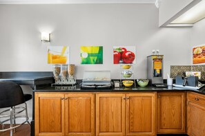 A kitchen with wooden cabinets, a black countertop, and various breakfast items.