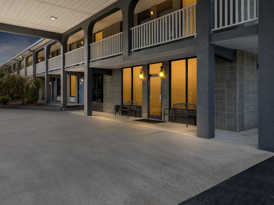 Un hotel con un espacio exterior techado, varios balcones y una zona de estar con sillas.