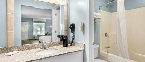 A bathroom with a sink, mirror, and a shower area.