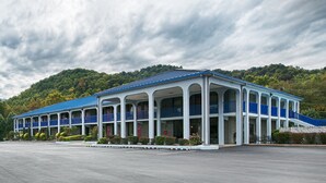 A large, single-story building with a blue roof and white columns, featuring multiple balconies and a covered walkway.