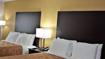 Una habitació d'hotel amb dos llits, una tauleta de nit amb una làmpada i un telèfon.