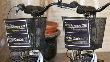 Dos bicicletas con cestas que llevan las etiquetas 'Hotel Alfonso XIII' y 'Hotel Carlos III' de Sercotel Hotels.