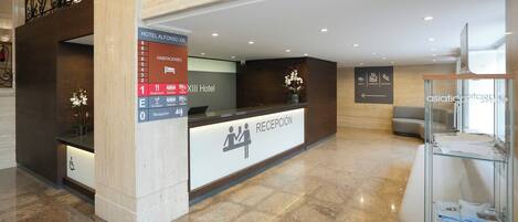 Una mesa de recepción de hotel con un cartel que indica el XIII Hotel y una zona de recepción.