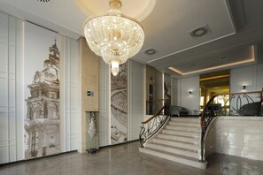 Eine imposante Treppe mit einem Kronleuchter, eine Wand mit Wandgemälde und ein modernes Interior-Design.