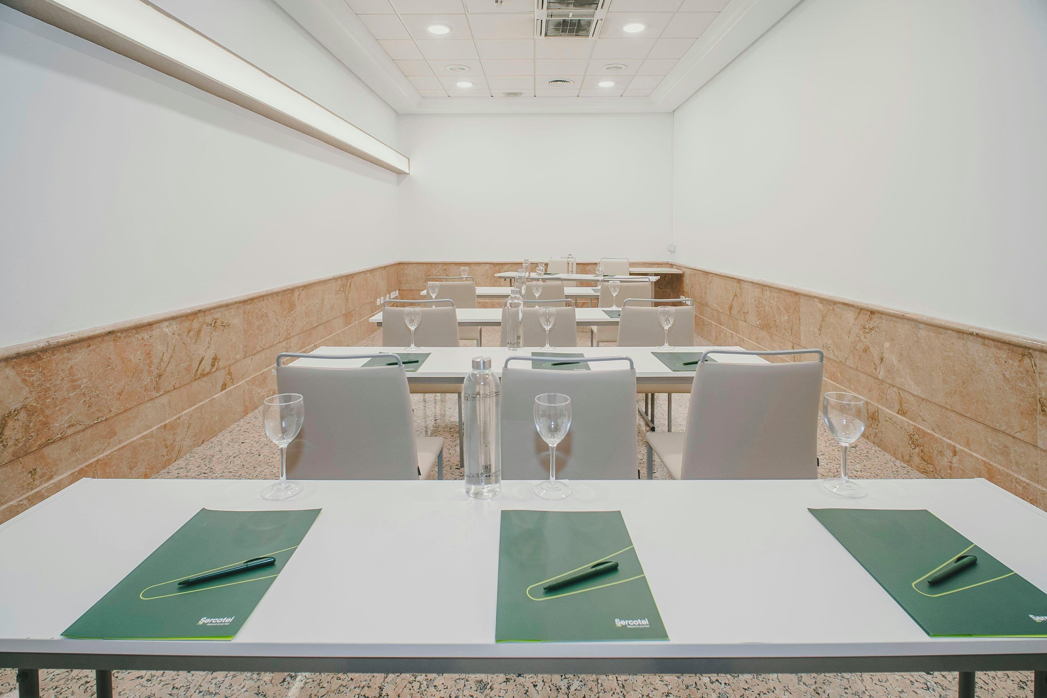 A conference room with tables, chairs, and glassware.