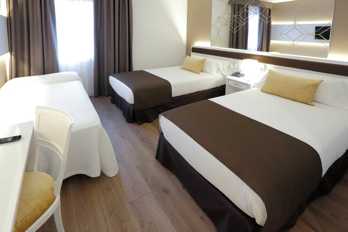 Una habitación de hotel con dos camas, un escritorio y una silla.