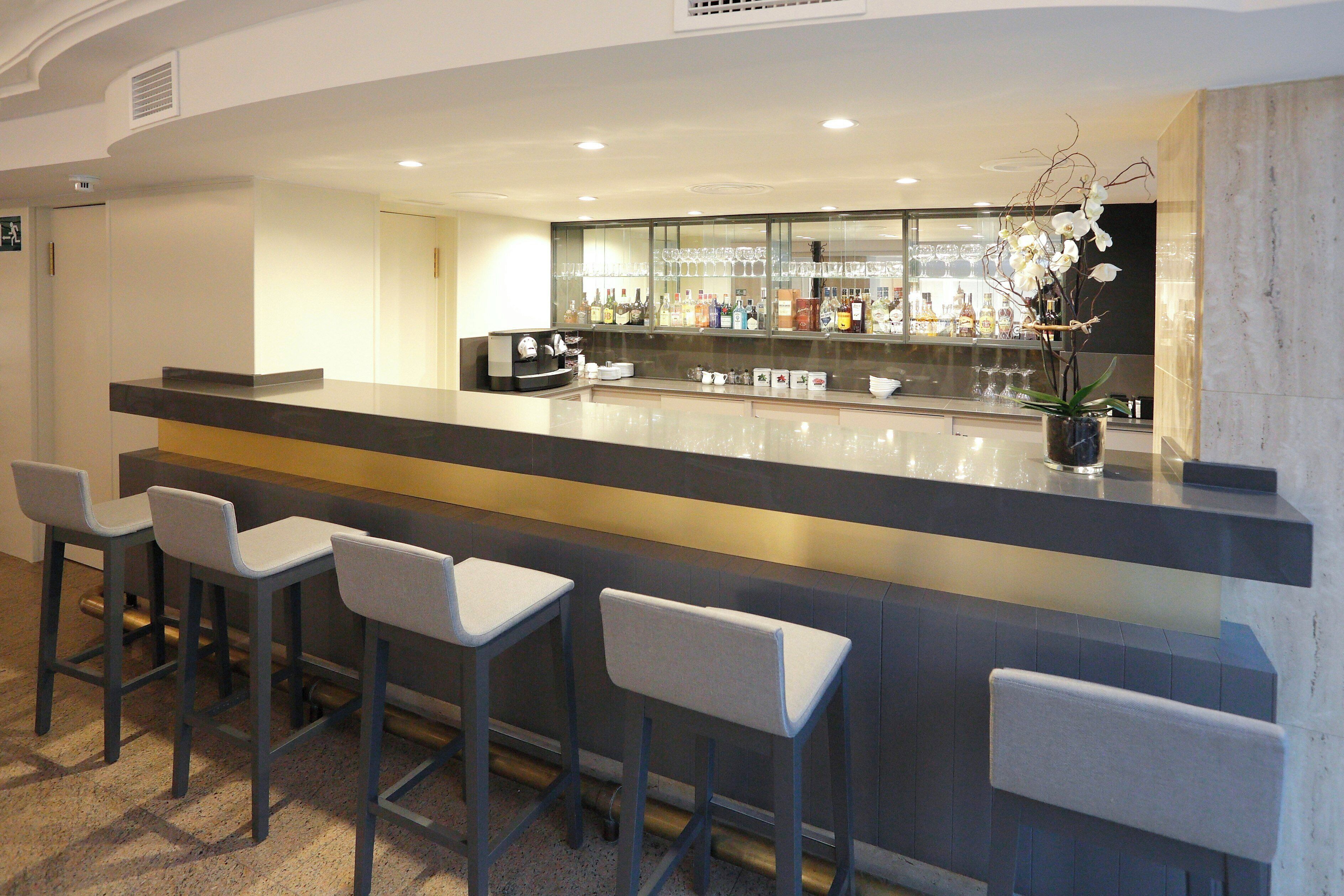 A bar area with a counter, bar stools, and a potted orchid.
