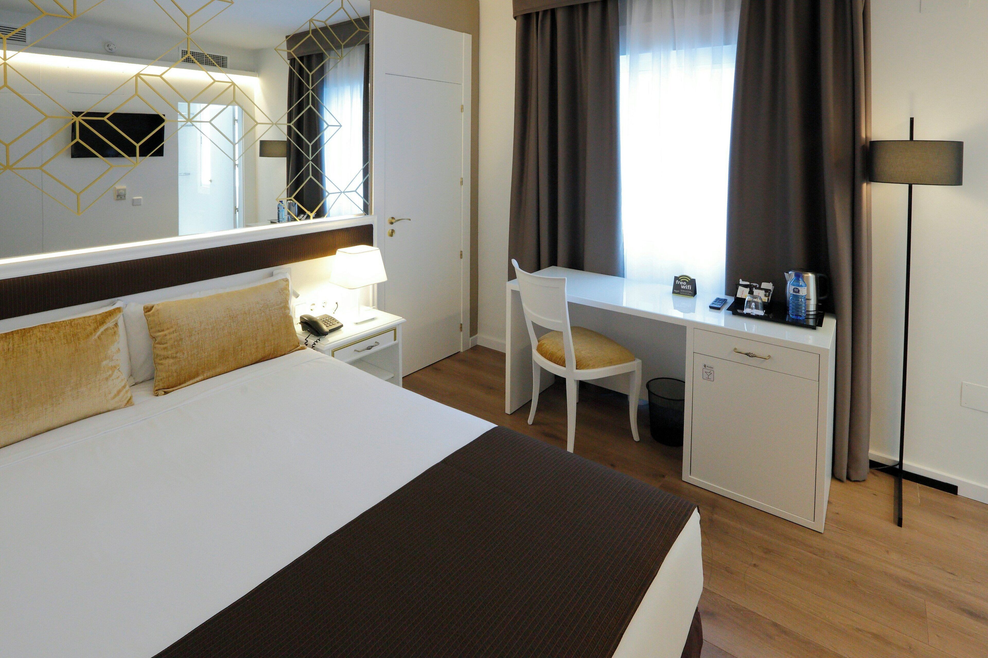 Une chambre d’hôtel équipée d’un lit, d’un bureau, d’une chaise et d’une petite armoire.