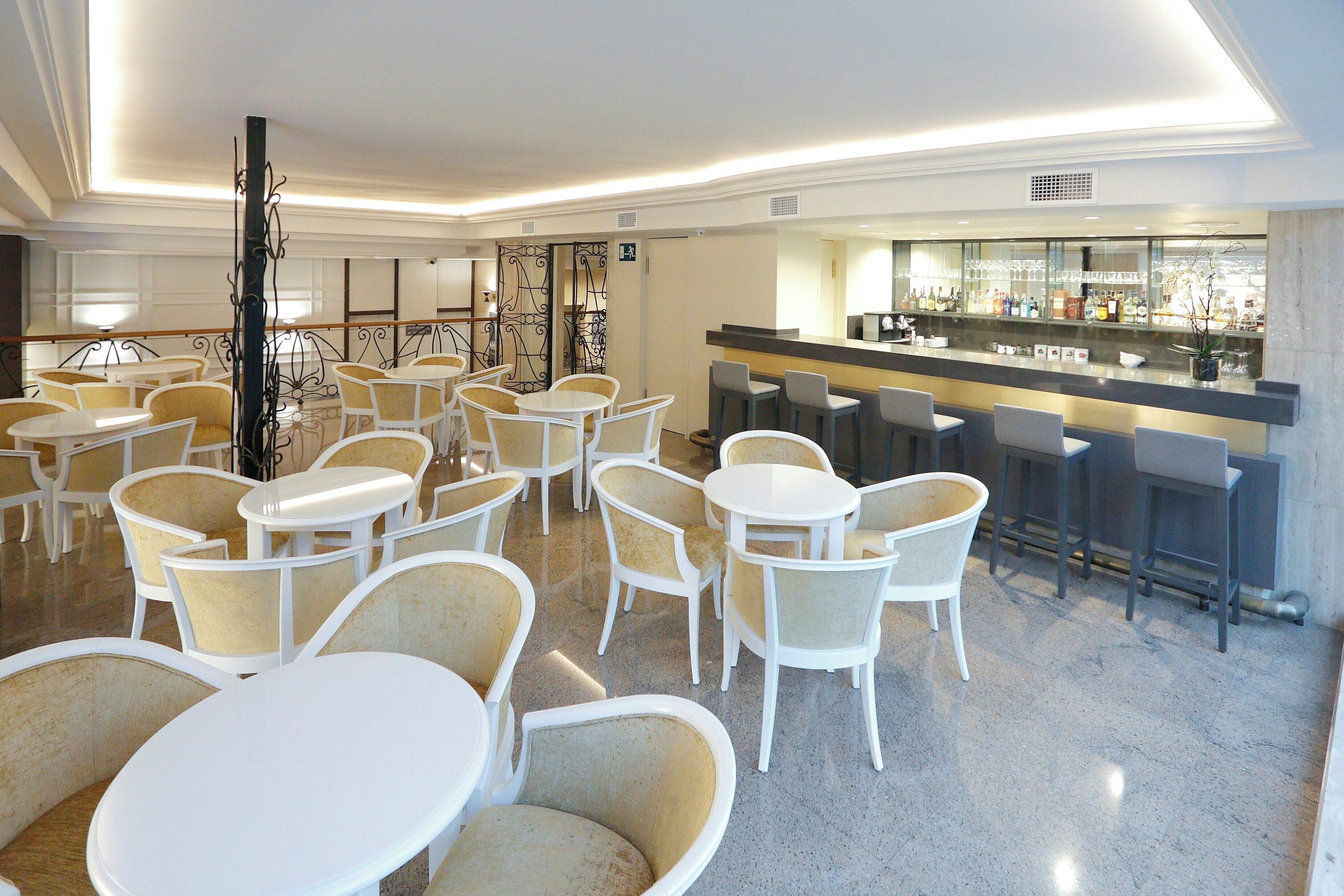 A hotel lobby with multiple seating areas, a bar, and a reception desk.