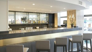 A bar area with a counter, bar stools, and a display of bottles and glasses.