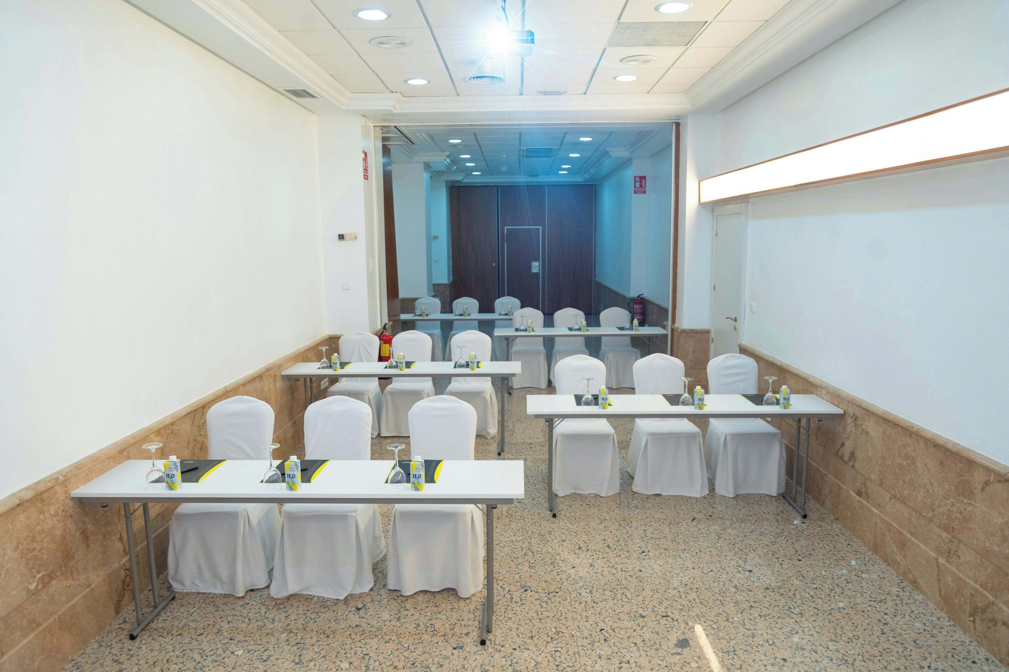 A conference room with tables, chairs, and a projector screen.