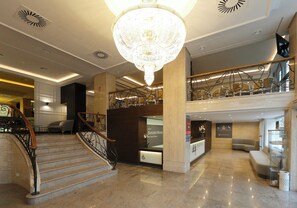 A hotel lobby with a grand chandelier, a reception desk, a staircase, and a seating area. - Hotel Sercotel Alfonso XIII (Cartagena)