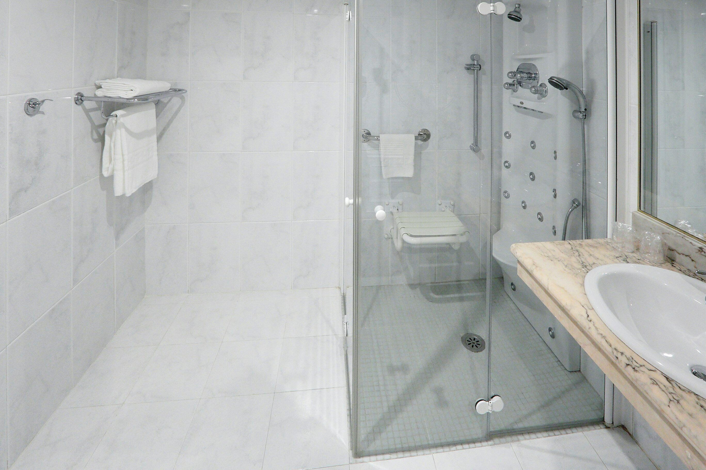 Une salle de bain moderne avec une douche à parois de verre, un comptoir en marbre et un lavabo blanc.