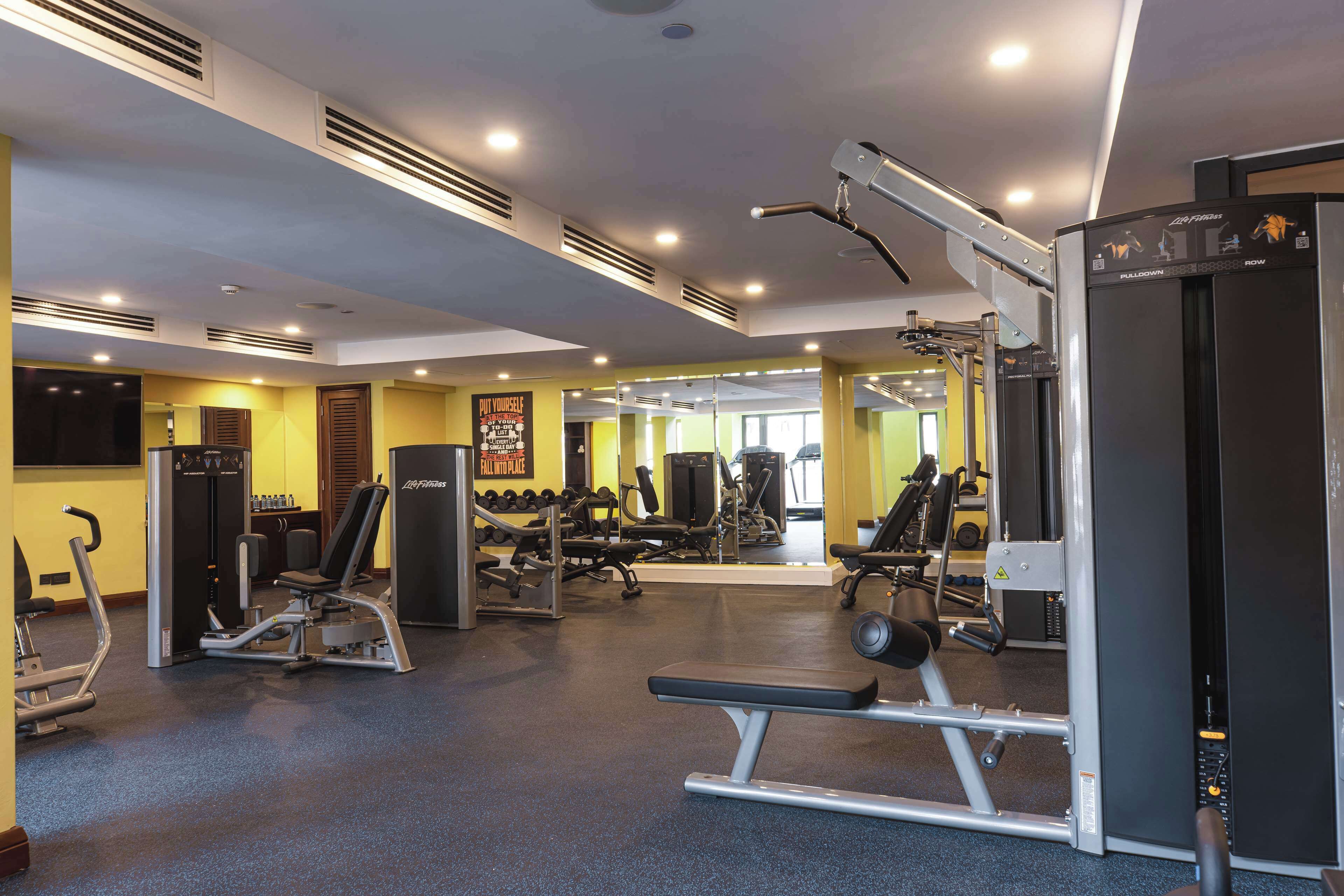 Un gimnasio con diverso equipo de ejercicio, incluyendo cintas de correr, máquinas de pesas y pesas libres.