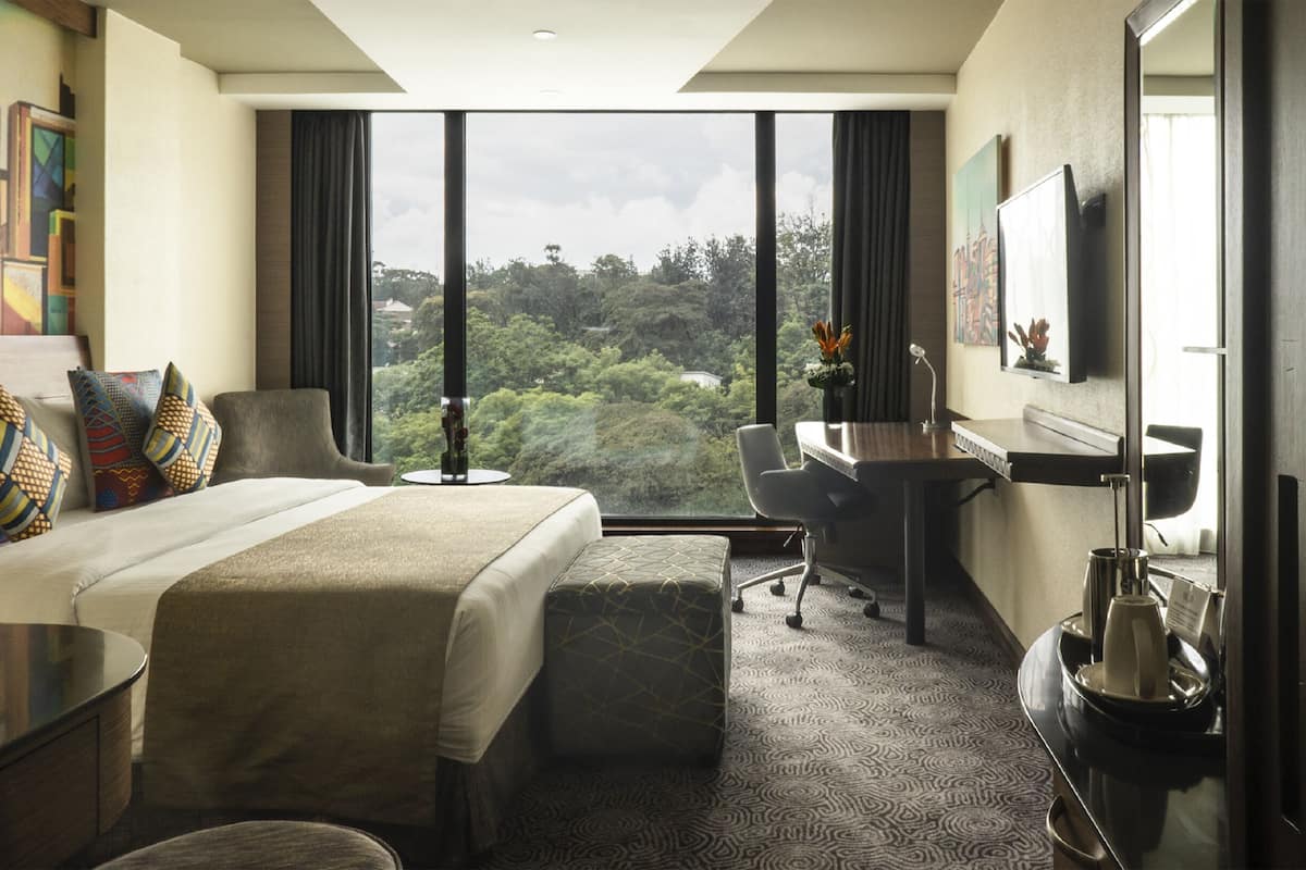 Ein Hotelzimmer mit einem großen Bett, einem Schreibtisch und Blick ins Freie.
