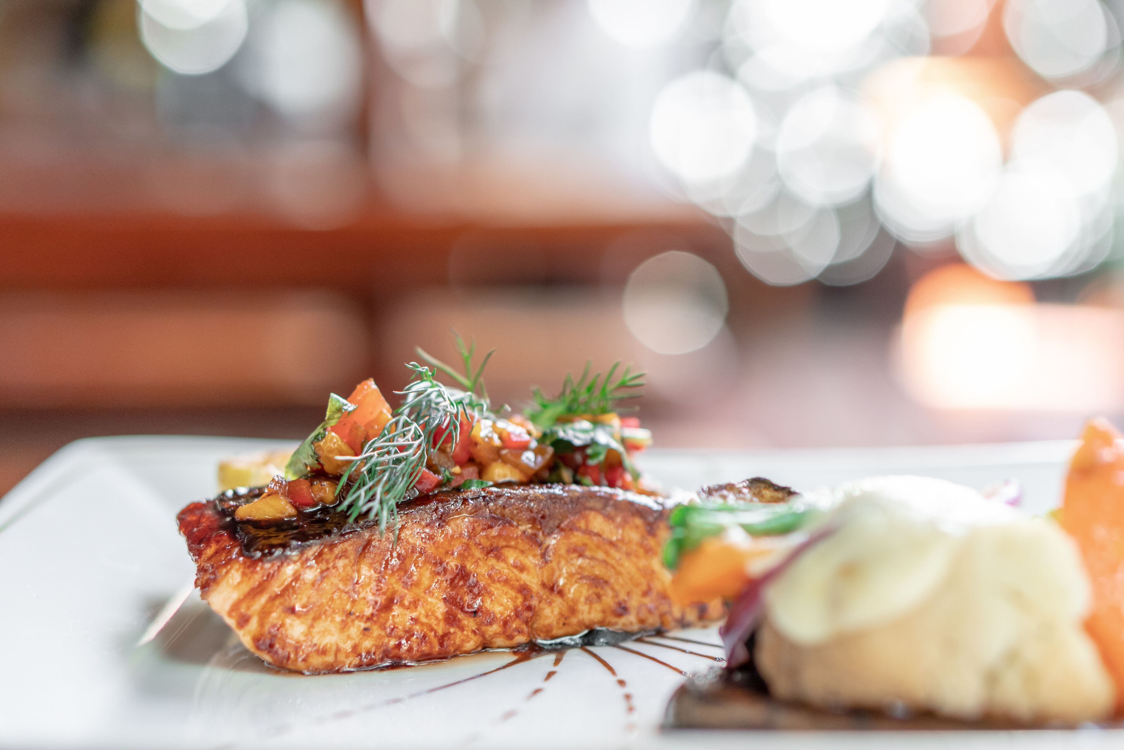 A plate of food with salmon, vegetables, and sauce.