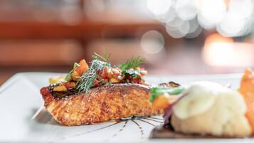 A plate of food with salmon, vegetables, and sauce.