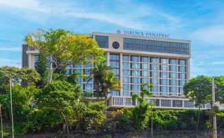 A modern building with the name "SAROVA PANAFRIC" on the facade, surrounded by lush greenery.