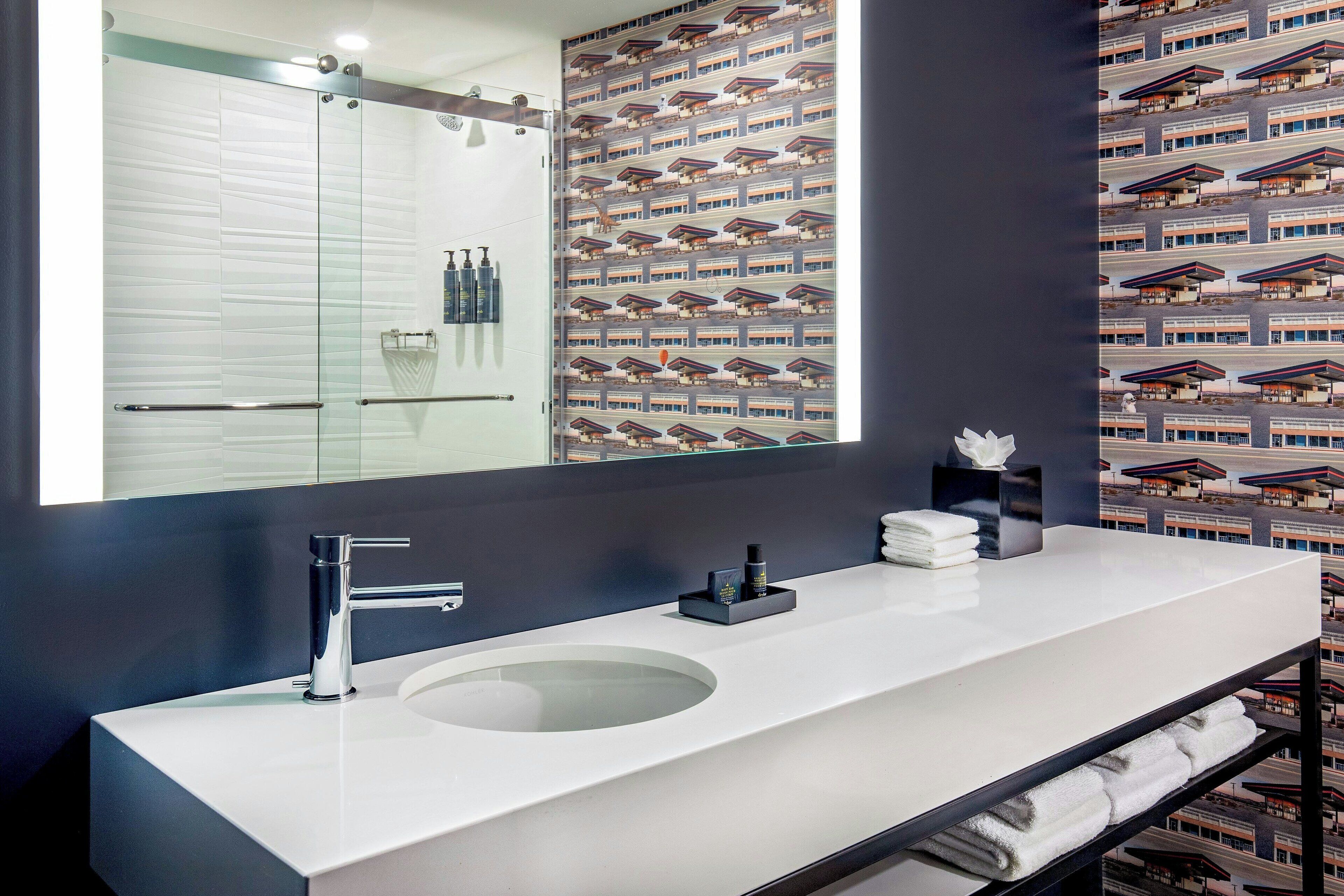 A modern bathroom with a large mirror, a round sink, and a towel rack.