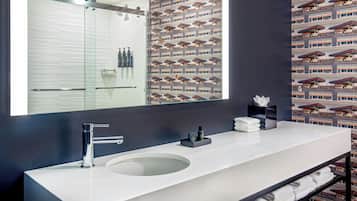 A modern bathroom with a large mirror, a round sink, and a towel rack.