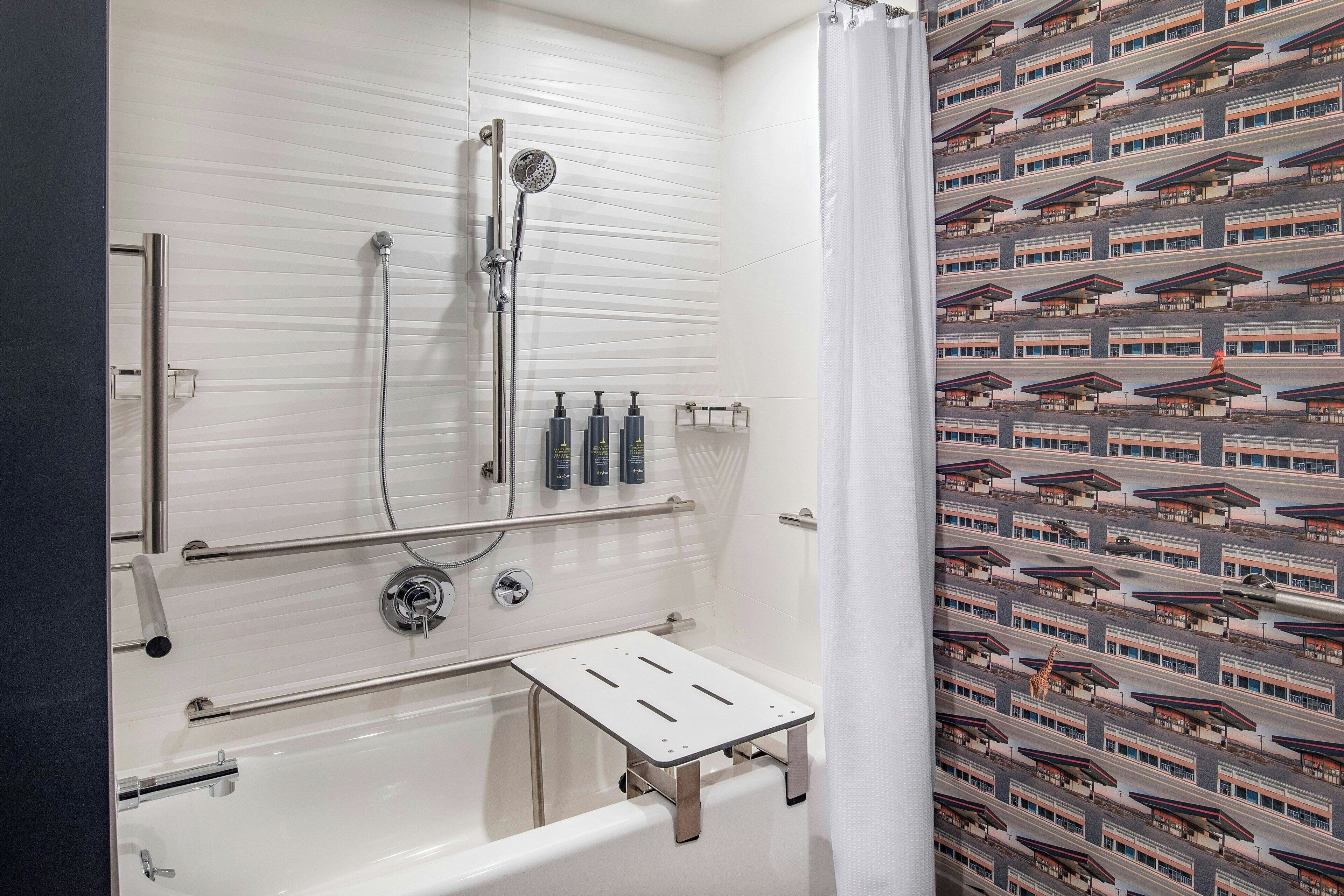 Ein modernes Badezimmer mit Badewanne, Dusche und Haltegriffen.