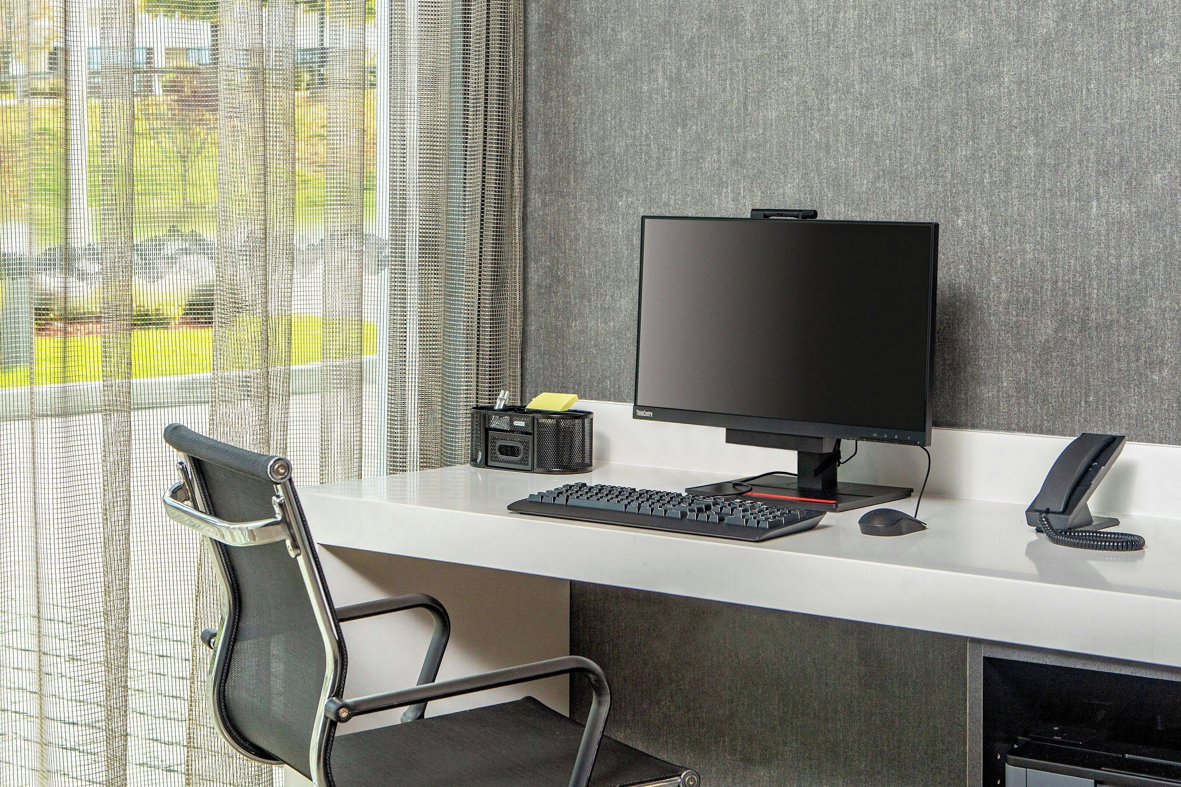 A modern office desk with a computer, keyboard, mouse, and telephone.