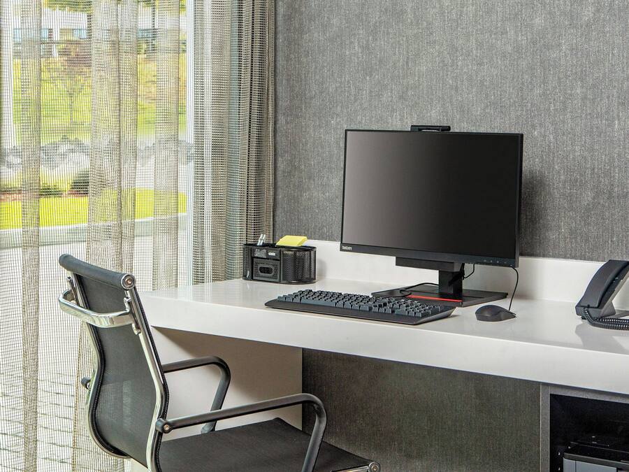 A modern office desk with a computer, keyboard, mouse, and telephone.