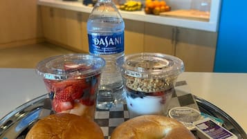 Ein Tablett mit einem Beutel, einem Sandwich, einer Flasche Dasani Wasser und zwei Portionen Joghurt-Parfaits.