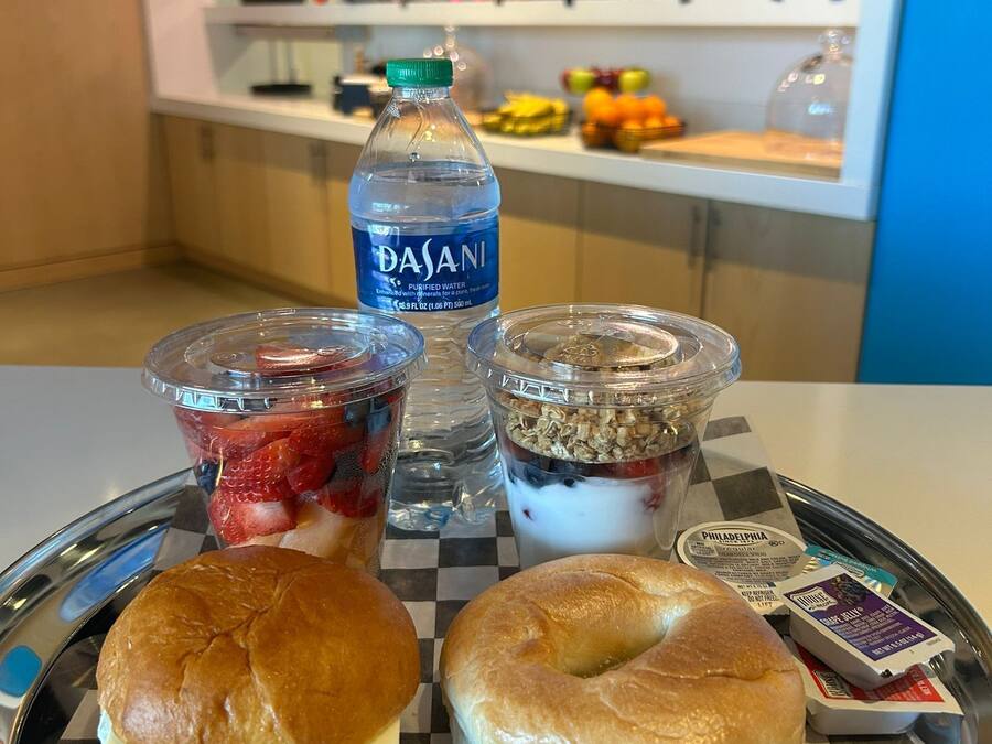 Ein Tablett mit einem Beutel, einem Sandwich, einer Flasche Dasani Wasser und zwei Portionen Joghurt-Parfaits.