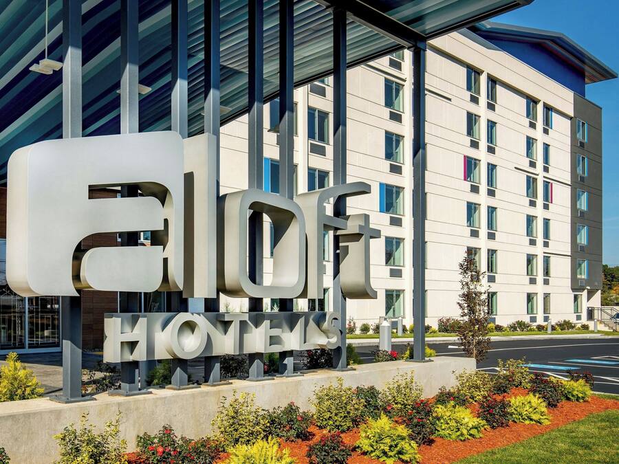 A hotel sign with the name "ELOFT HONEYVAH" and a modern building in the background.