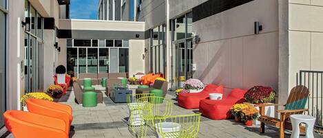 An outdoor seating area with modern chairs and sofas, a fire pit, and potted plants.