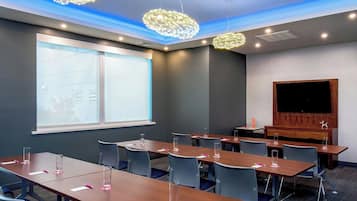 A conference room with long tables, chairs, and a large screen.