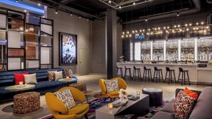 A modern lounge area with sofas, chairs, and a bar with stools. - Aloft by Marriott Framingham (Framingham)