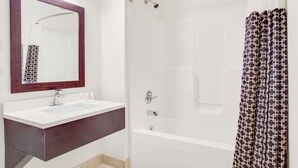 A bathroom with a white sink, dark vanity, a large mirror, a bathtub, and a shower curtain. - Super 8 by Wyndham Dalton (Dalton)
