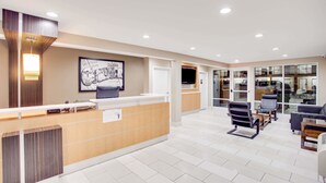 A reception area with a wooden reception desk, a framed welcome sign, and a seating area with chairs and a coffee table. - Super 8 by Wyndham Dalton (Dalton)