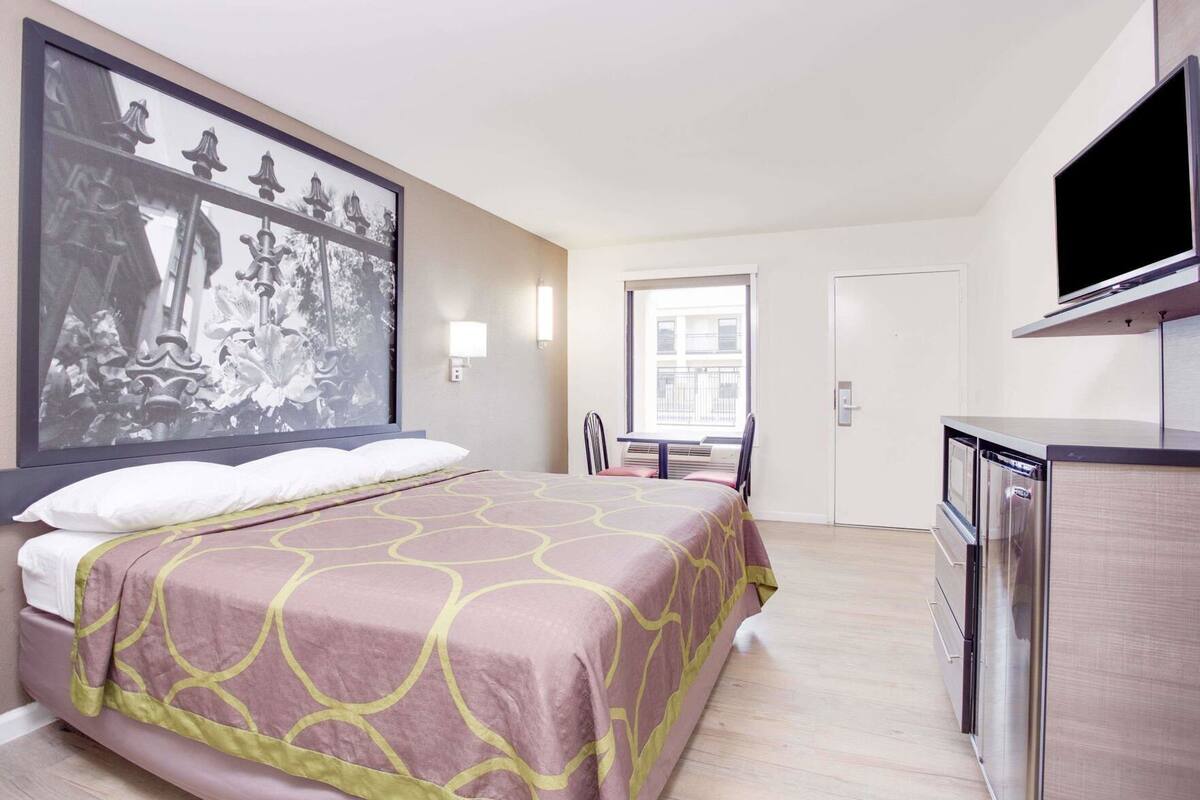 Ein Hotelzimmer mit Bett, Schreibtisch, Fernseher und großem Fenster.