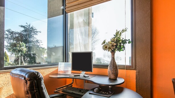 Un bureau moderne, équipé d’un ordinateur, d’un clavier, d’une souris et d’un vase avec des fleurs.