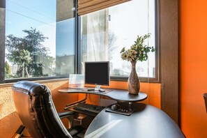 A modern office desk with a computer, keyboard, mouse, and a vase with flowers. - Quality Inn & Suites Macon North (Macon)