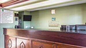 Un comptoir d’accueil avec un revêtement en bois, un écran numérique et une enseigne indiquant « Quality Inn & Suites ».