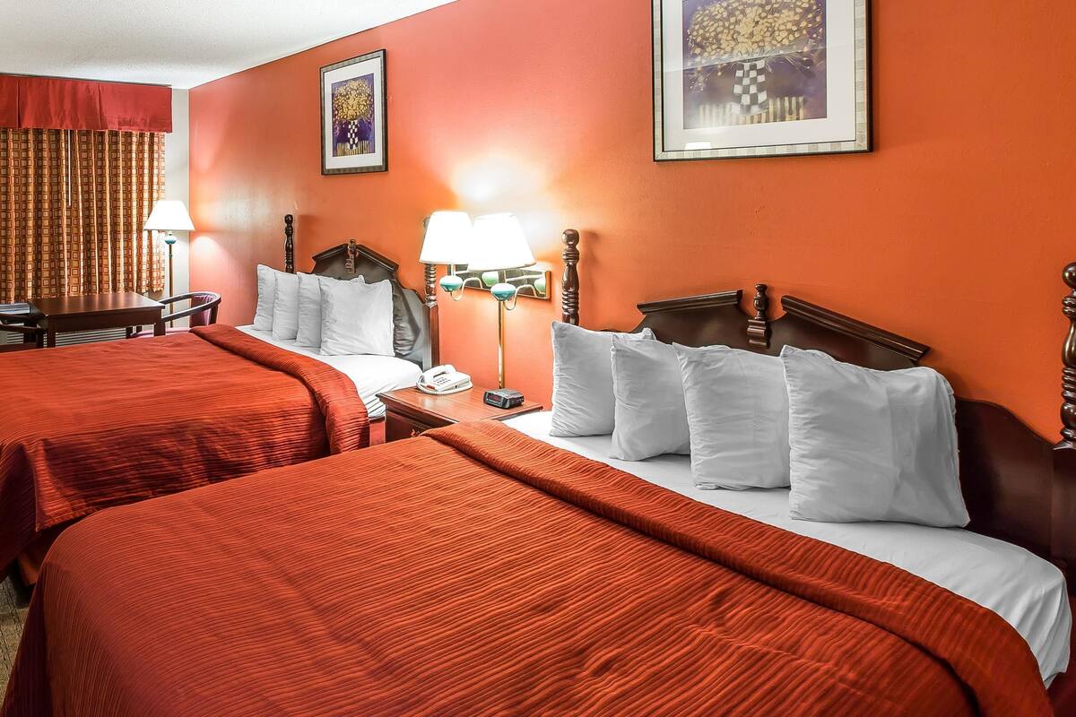 A hotel room with two beds, a desk, and a chair.