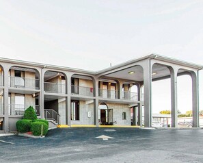 A multi-story motel with a central courtyard, balconies, and a parking area.