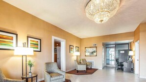 A spacious lobby with a chandelier, patterned armchairs, and artwork on the walls.