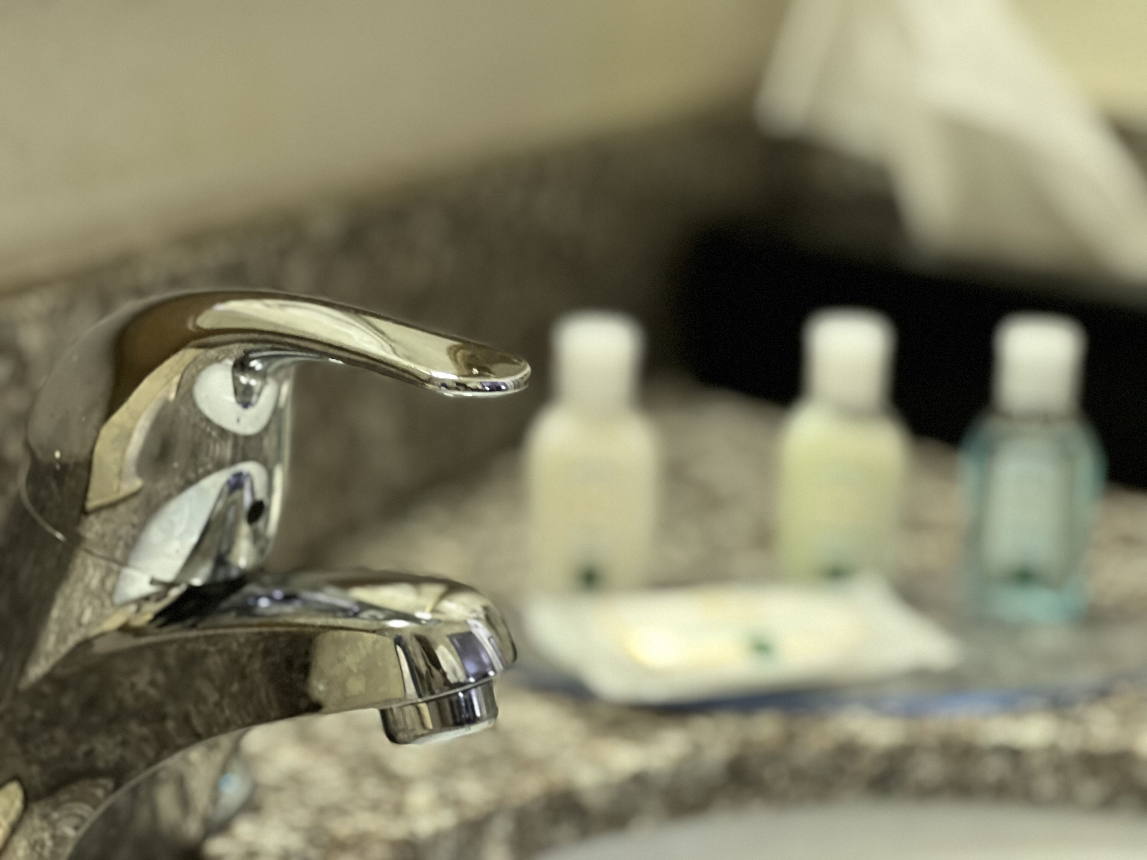 A bathroom sink with a chrome faucet and a soap dispenser.