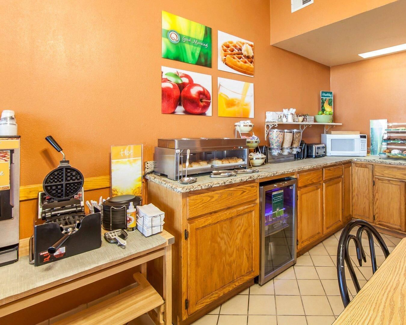 A breakfast bar with waffle maker, toaster, and coffee machine.