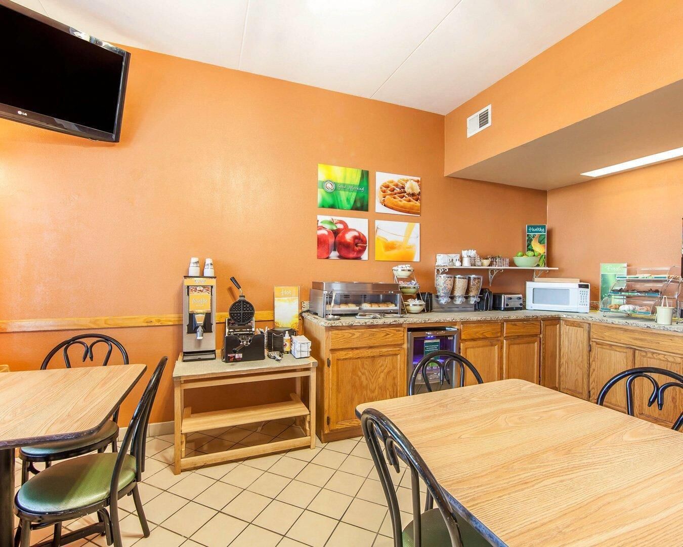 Un área de desayuno con televisión de pantalla plana, máquina para hacer gofres, cafetera y microondas.