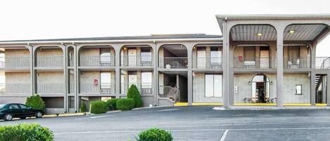A multi-story motel with a central entrance, balconies, and a parking area.