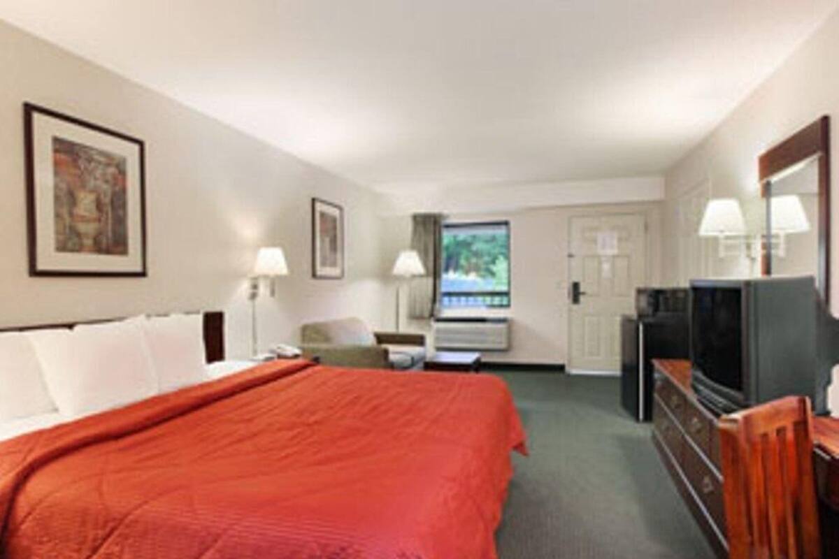Una camera d'albergo con un letto, una scrivania, una televisione e una finestra con vista.