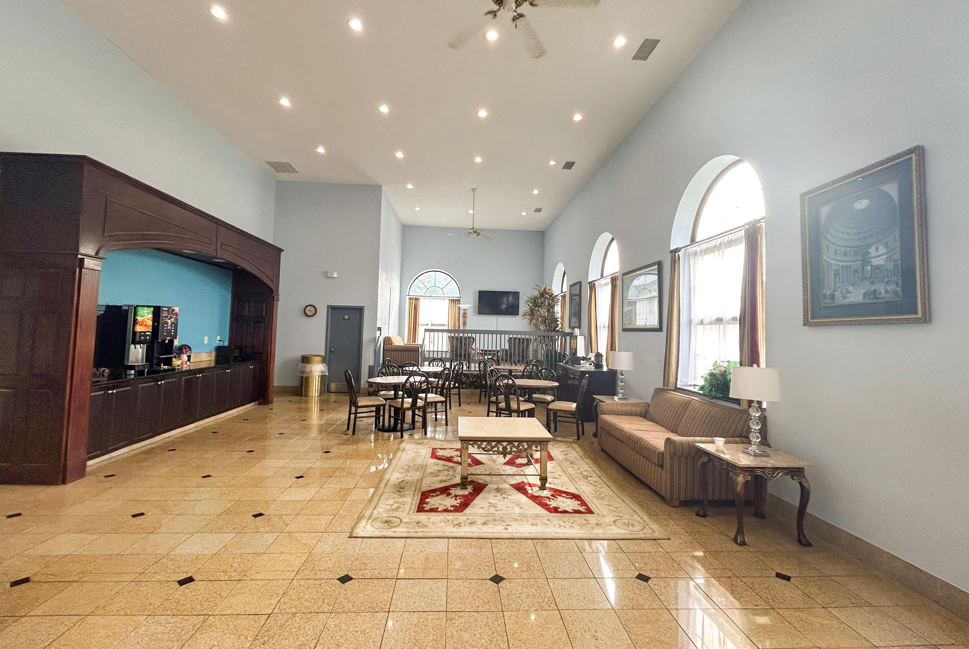 Un amplio vestíbulo de hotel con una recepción, zona de estar y comedor.