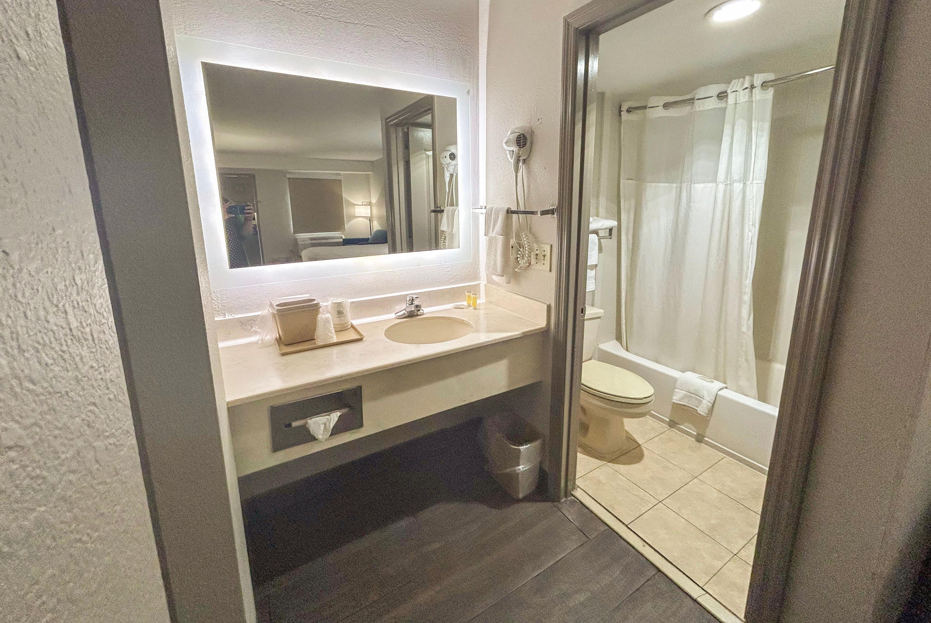 A bathroom with a sink, mirror, and shower.